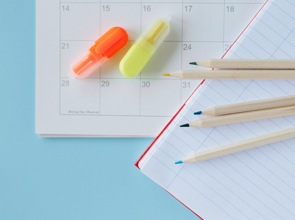 Pencils and highlighters sitting on top of a calendar